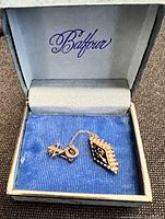 Photo showing the Kappa Delta sorority pin set inside a Balfour-branded box with blue interior lining.