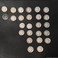 Overview of 25 Mercury silver dimes arranged in rows on a black surface