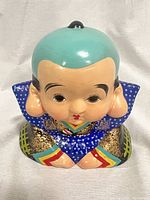 Front and slightly tilted view of the ceramic samurai boy doll piggy bank showing detailed painted kimono and facial features.