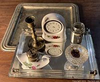 Photo of candle holders, trays, clock, and glass items grouped on wooden surface.