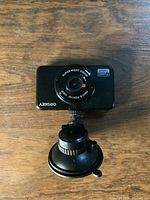 Front view of Orskey dash camera showing lens and suction cup mount on wooden surface.