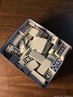 Top view of multiple white domino tiles with various colored dots inside a box.