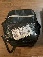 Front view of black Trunab food delivery backpack with instruction sheet in clear pocket