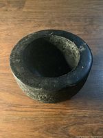 Granite manual grinder stone side view showing rough texture and circular hollow.