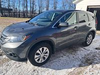 Driver’s side view of grey 2014 Honda CR-V showing body and wheels