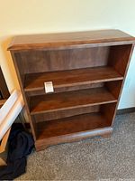 Front view of wooden bookshelf showing three shelves and the curved top design.