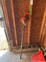 Full view of the upright manual rotary drum pump showing long intake pipe, orange discharge spout, and hand crank.