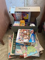 Wide view of the lot inside a plastic bin showing assortment of puzzles, games, crayons, and a baseball