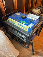 Angle view showing blue housing, tubular steel frame, fuel cap, and operation manual on top