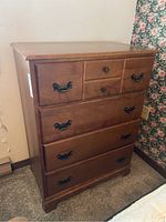 Front view of wooden highboy dresser showing drawer configuration and handles.
