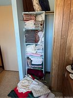 Shelving unit with folded linens including sheets and towels stacked in different colors and patterns