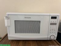 Front view of white Frigidaire microwave with door closed and control panel visible on right.