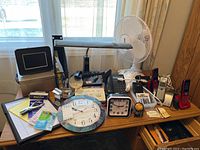 Main photo showing entire desk with multiple electronic items and office supplies arranged on it in front of a window