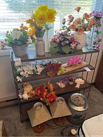 Front view of metal shelf with floral arrangements and decorative items placed on it, showing size and shelving detail.