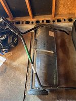 Top angled view of the Yard Commander sweeper showing handlebar and sweeping surface.