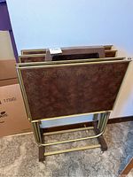 Four vintage TV dinner trays positioned in the gold-tone metal stand showing overall condition and storage setup.