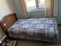 Full view of twin size bed with mattress and wooden headboard by window.