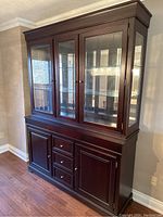 Front-left angle view of the rosewood display cabinet showing glass doors and wood paneled lower cabinet with drawers.
