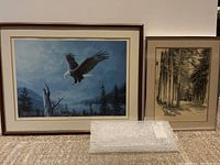 Framed nature artworks on carpet floor; left shows colored eagle print, right shows black and white forest sketch