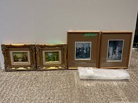 Four artworks displayed on floor showing two small ornate framed landscape paintings and two larger framed figurative prints.
