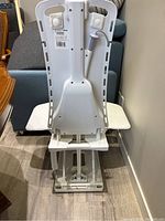 Rear view of bathlift showing white plastic backrest and mechanical base.