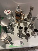 Photo showing wine steins and metal decorative jugs on table