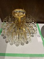 Side angle view showing curved gold arms extending from center and large faceted crystal drops hanging from each arm.