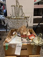 Full view of chandelier suspended over box containing extra crystals and instruction sheet