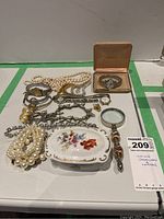 Full lot showing costume jewellery, watches, and ceramic jewellery box on display surface.