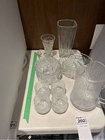 Overall lot displayed on surface showing pitcher, tumblers, bowls and vases