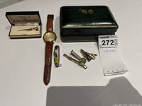 Overview of all cuff links, watch and tie clips laid out on table