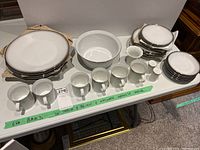 Full set of Rosenthal dishes including plates, bowls, cups, creamer, sugar bowl, salt and pepper shakers arranged on table with visible silver rims.