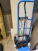 Close-up of the folding luggage cart handle and wheel assembly, showing condition and materials.