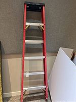 Full view of the Featherlite fiberglass step ladder showing four metal steps, red fiberglass rails and black top platform.