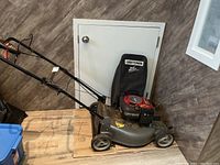 Side view of complete lawn mower showing deck, handle, wheels and catcher bag