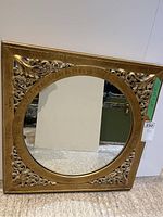 Full front view of the gold ornate framed mirror showing square frame and round mirror center