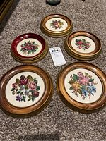 Five round framed petit point floral pictures arranged on carpet showing overall lot condition and style.