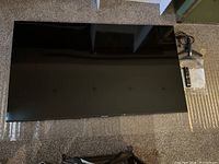 Front view of Samsung TV face up on bubble wrap with accessories at top right