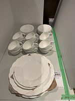 White Wedgwood Oceanside bone china plates, cups, and saucers arranged on a table, showing the large plates at the front and cups behind.