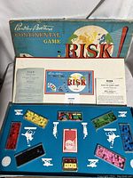 Game setup inside box with cards, dice, colored playing pieces in compartments, and instructions.