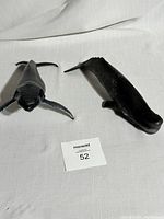 Two hard plastic whale toys side by side on a white fabric background with auction tag number 52 visible.