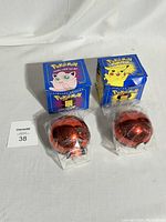 Two unopened limited edition 1999 Pokemon trading cards in blue boxes featuring Pikachu and Jigglypuff, each with red Pokeball display cases inside plastic sleeves.