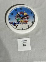 Front view of M&M's vintage candy wall clock showing colorful M&M characters on blue background within white round frame.