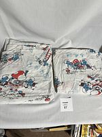 Folded vintage Smurfs bed sheets set, showing the printed fabric with cartoon characters and mushrooms.