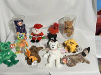 Full collection of 12 vintage Beanie Baby plush toys arranged on white sheet.