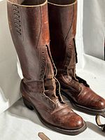 Front view of tall vintage brown leather riding boots with lace-up fronts, showing wear and creasing.