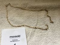 Full view of gold chain necklace laid on a towel with MaxSold card