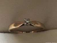 Close-up photo of antique 10k gold ring showing the small diamond set in the center and the tapered band with split sides.