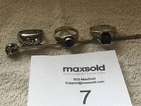 Photo showing two sterling silver rings and one silver stick pin arranged on a towel surface.