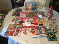 Full view of assorted craft supplies laid on a table showing markers, sticker sheets, cards, small packaged items, and booklets.